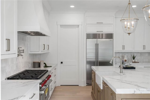 kitchen with light stone counters, premium range hood, and white cabinetry