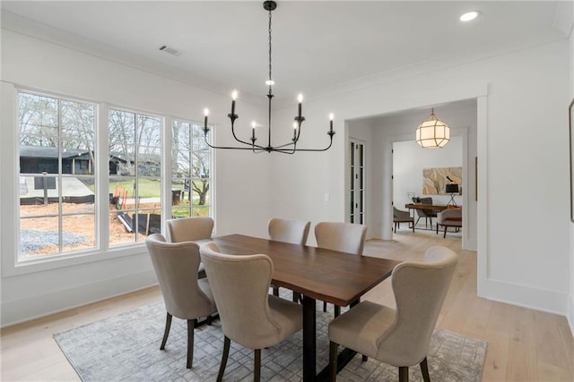 dining room with light hardwood / wood-style flooring, crown molding, and a notable chandelier