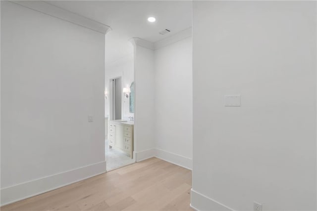 empty room with sink, ornamental molding, and light hardwood / wood-style flooring