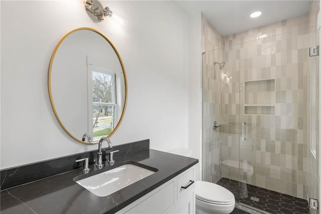 bathroom with an enclosed shower, vanity, and toilet