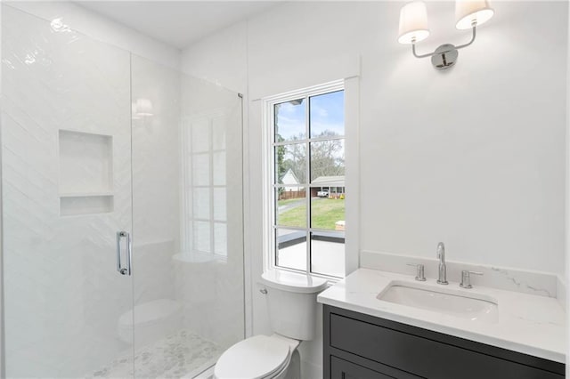 bathroom featuring vanity, toilet, and a shower with door