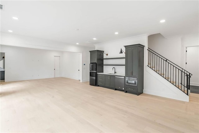 unfurnished living room with sink, crown molding, and light hardwood / wood-style floors