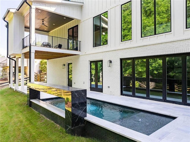 back of property with ceiling fan, a yard, a balcony, and a patio