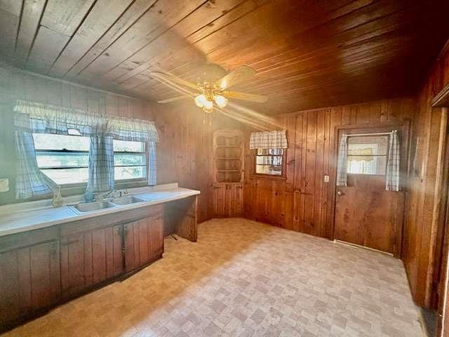 office area featuring ceiling fan, wood walls, wooden ceiling, and sink