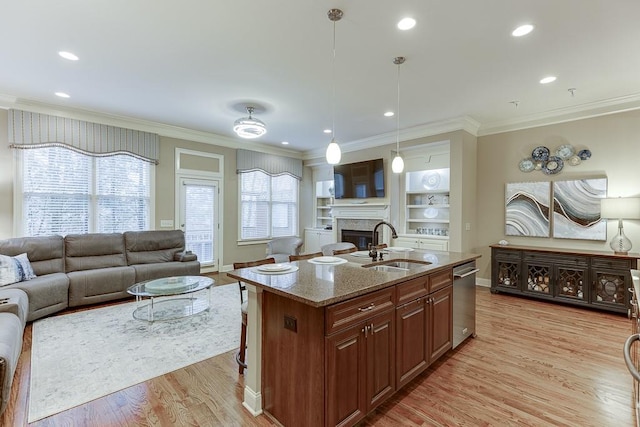 kitchen with a sink, light stone countertops, light wood-style floors, and open floor plan