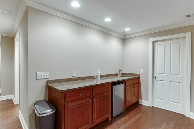 kitchen featuring visible vents, a sink, dark wood finished floors, crown molding, and dishwasher