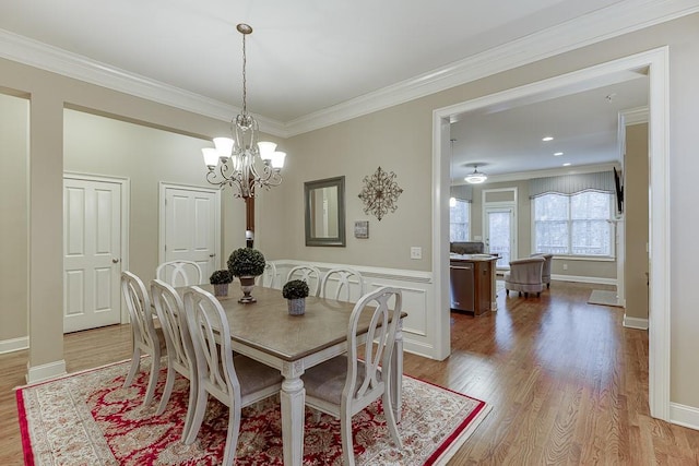 dining space featuring baseboards, light wood-style floors, a chandelier, and crown molding