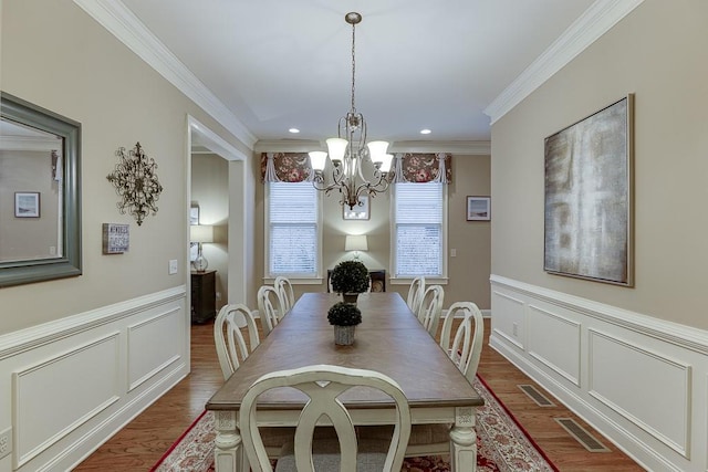 dining space with visible vents, a decorative wall, ornamental molding, and a chandelier