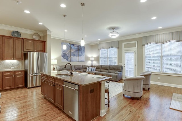 kitchen featuring ornamental molding, brown cabinetry, appliances with stainless steel finishes, and a sink