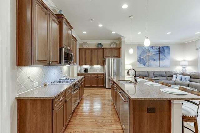 kitchen with open floor plan, a breakfast bar area, ornamental molding, appliances with stainless steel finishes, and a sink