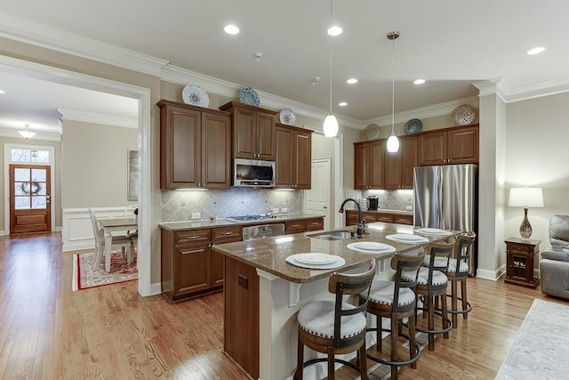 kitchen with a sink, a breakfast bar area, light wood-style floors, and stainless steel appliances