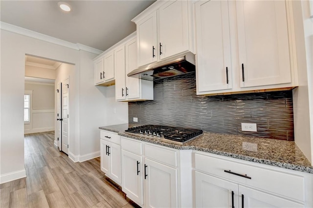 1620 Branthaven Ln, Auburn, GA 30011 - kitchen with under cabinet range hood, stainless steel gas stovetop, ornamental molding, light stone counters, and white cabinets