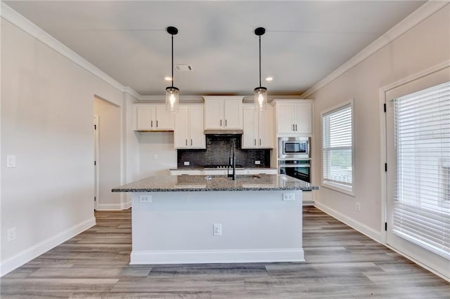 1620 Branthaven Ln, Auburn, GA 30011 - kitchen featuring stainless steel appliances, white cabinets, dark stone counters, crown molding, and a center island with sink
