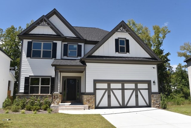 view of front facade featuring a front yard, stone siding, board and batten siding, and driveway