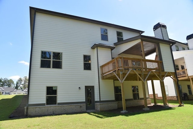 rear view of house with a yard, brick siding, a wooden deck, and a chimney