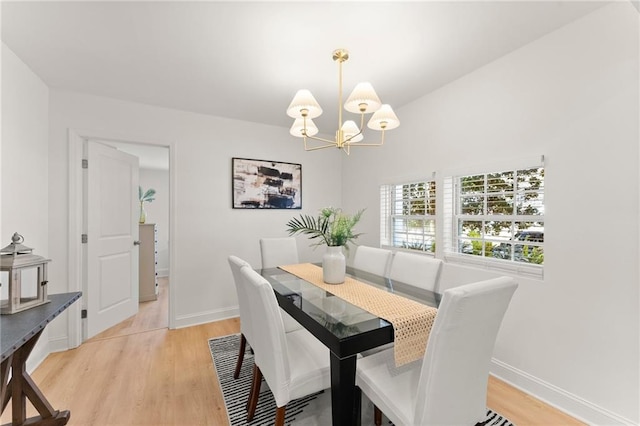 dining space with light wood-type flooring, baseboards, and a notable chandelier