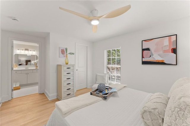 bedroom featuring ensuite bath, light wood-style floors, baseboards, and ceiling fan