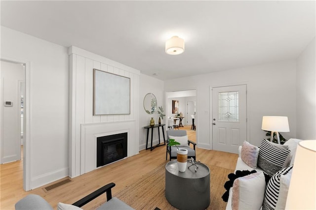 living area with visible vents, a fireplace, baseboards, and wood finished floors