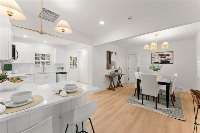 kitchen featuring visible vents, appliances with stainless steel finishes, white cabinetry, pendant lighting, and a sink