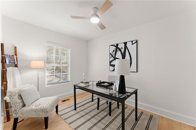 office with visible vents, light wood-style flooring, baseboards, and a ceiling fan