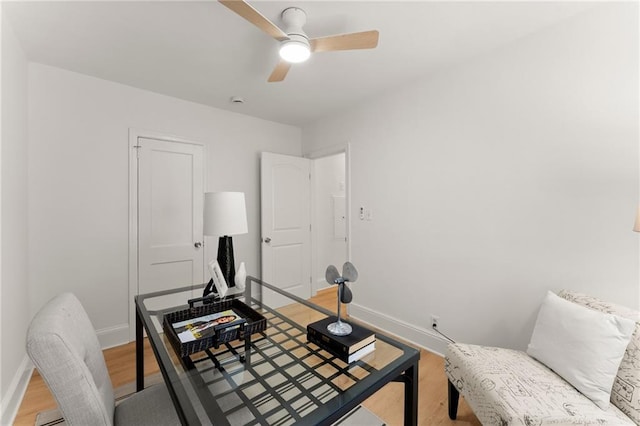 home office featuring light wood finished floors, a ceiling fan, and baseboards