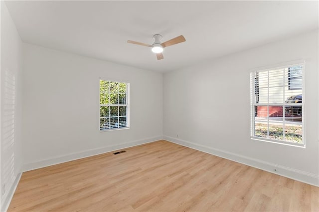 unfurnished room with light wood finished floors, a ceiling fan, visible vents, and baseboards