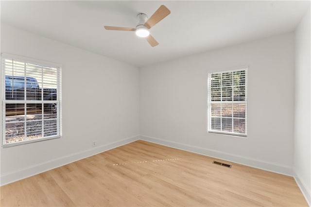 unfurnished room with visible vents, light wood finished floors, a ceiling fan, and baseboards