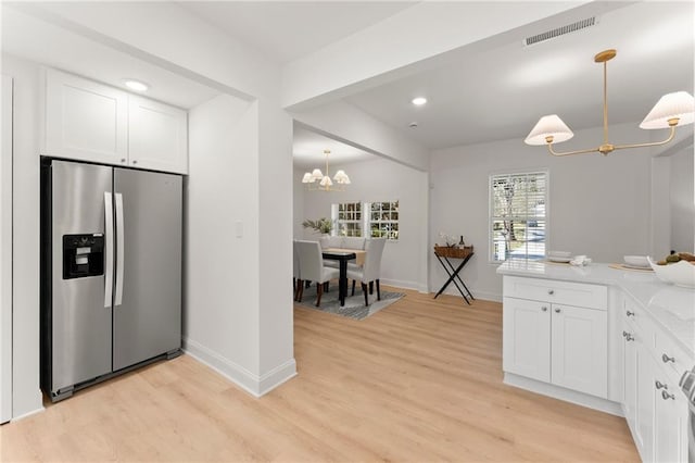 kitchen featuring visible vents, light wood finished floors, stainless steel fridge with ice dispenser, white cabinetry, and a notable chandelier