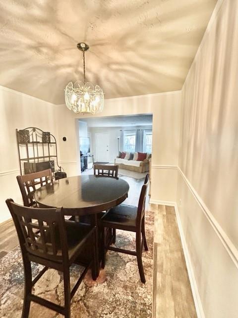 dining space featuring an inviting chandelier, baseboards, and wood finished floors