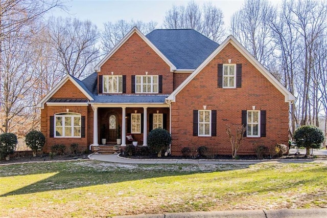 traditional home featuring brick siding, a porch, and a front yard