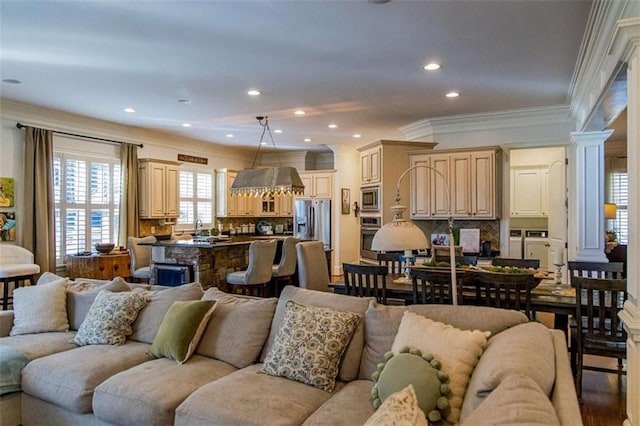 living room featuring decorative columns, washer and clothes dryer, wood finished floors, crown molding, and recessed lighting