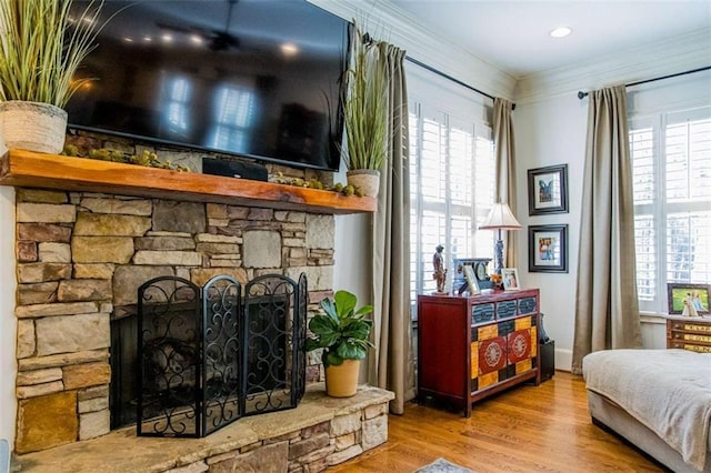 interior space featuring a stone fireplace, crown molding, and wood finished floors