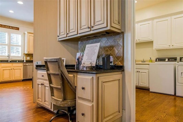 kitchen with dark countertops, light wood finished floors, washer and clothes dryer, and stainless steel dishwasher