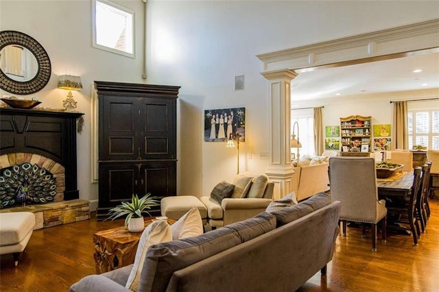 living area featuring visible vents, a fireplace, dark wood finished floors, and decorative columns