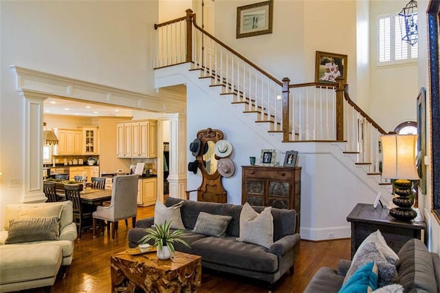 living room with stairs, dark wood-type flooring, and ornate columns