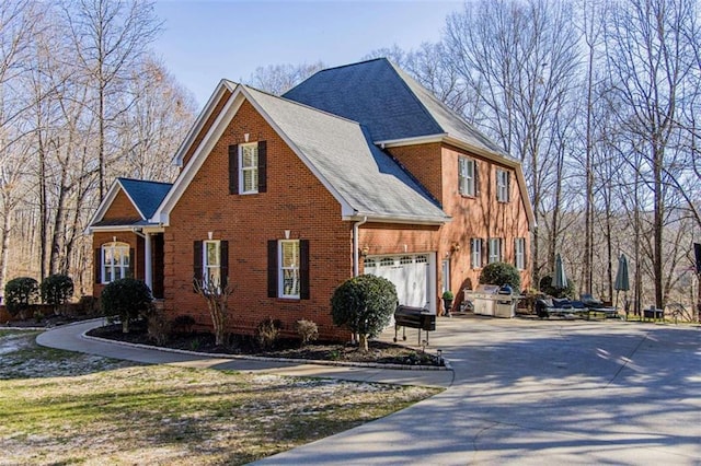 view of front of property featuring an attached garage, driveway, and brick siding