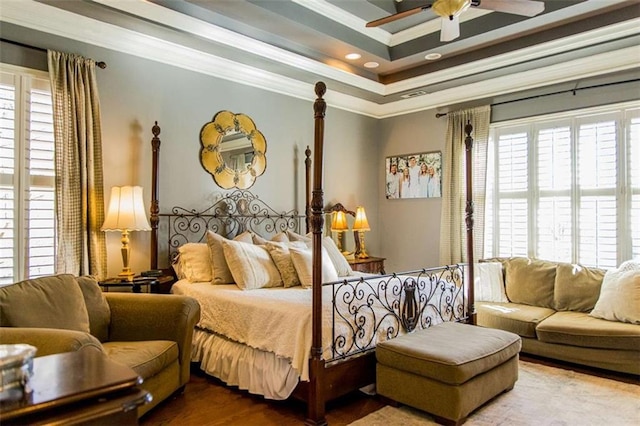 bedroom with ceiling fan, a tray ceiling, crown molding, and wood finished floors