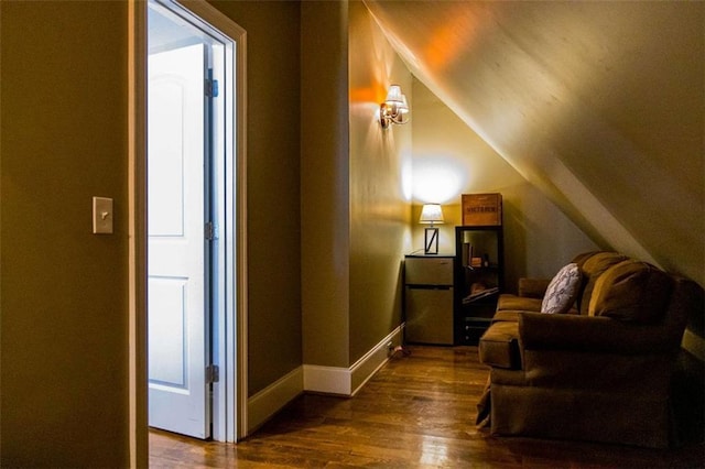 living area with baseboards, vaulted ceiling, and dark wood-style flooring