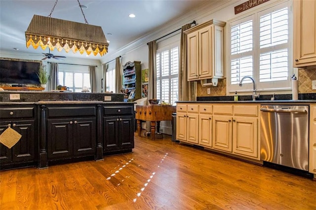 kitchen with dark countertops, ornamental molding, open floor plan, and stainless steel dishwasher