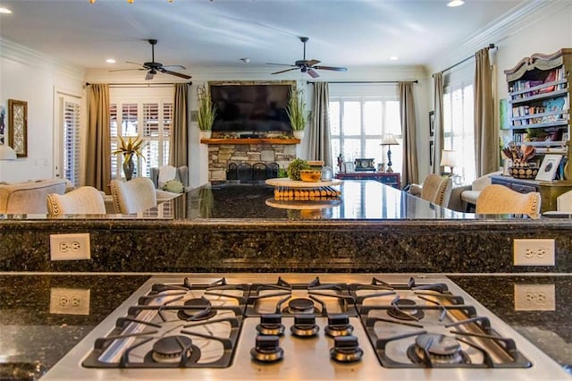 kitchen with dark stone countertops, a fireplace, open floor plan, and crown molding