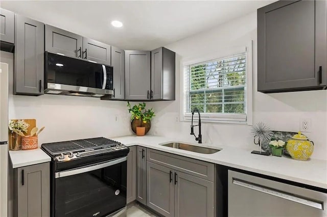 kitchen featuring stainless steel appliances, sink, and gray cabinetry