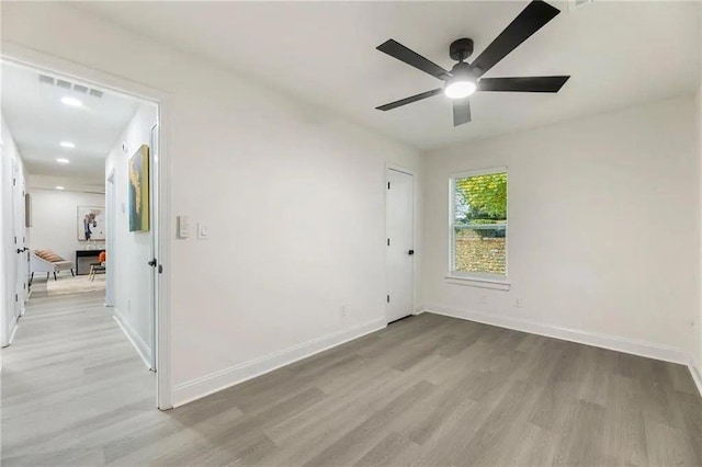 spare room with ceiling fan and light wood-type flooring