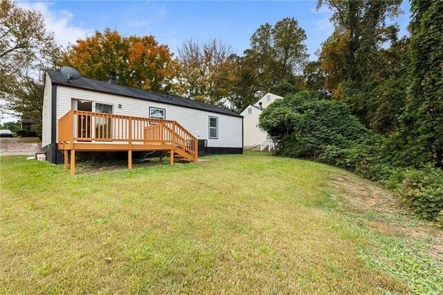 rear view of property featuring a yard and a deck