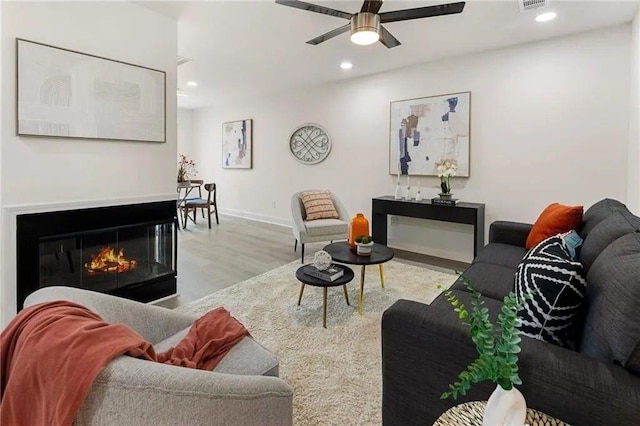 living room with ceiling fan and light hardwood / wood-style flooring