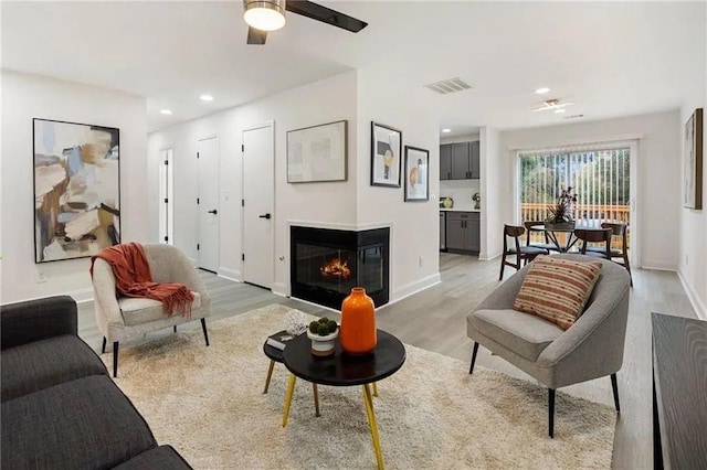 living room with ceiling fan and light hardwood / wood-style flooring