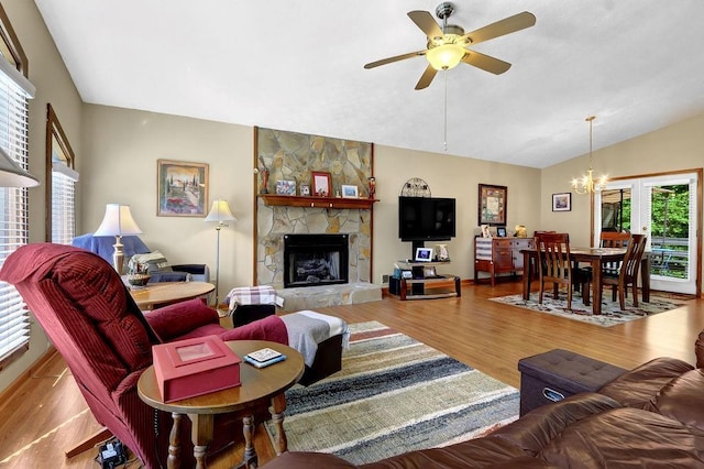 3491 Birchwood Trl, Snellville, GA 30078 - living room with a chandelier, vaulted ceiling, wood finished floors, a stone fireplace, and ceiling fan