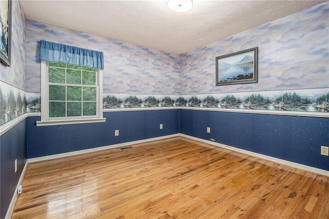 5247 Yeager Rd, Douglasville, GA 30135 - unfurnished room featuring wood finished floors, wallpapered walls, a textured ceiling, baseboards, and a wainscoted wall