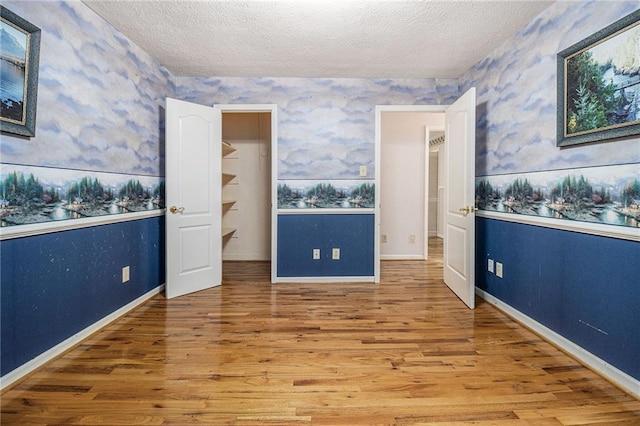 5247 Yeager Rd, Douglasville, GA 30135 - unfurnished room featuring wallpapered walls, wood finished floors, baseboards, and a textured ceiling