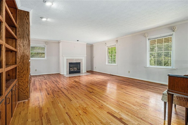 5247 Yeager Rd, Douglasville, GA 30135 - unfurnished living room with crown molding, a textured ceiling, light wood-style floors, healthy amount of natural light, and a tiled fireplace