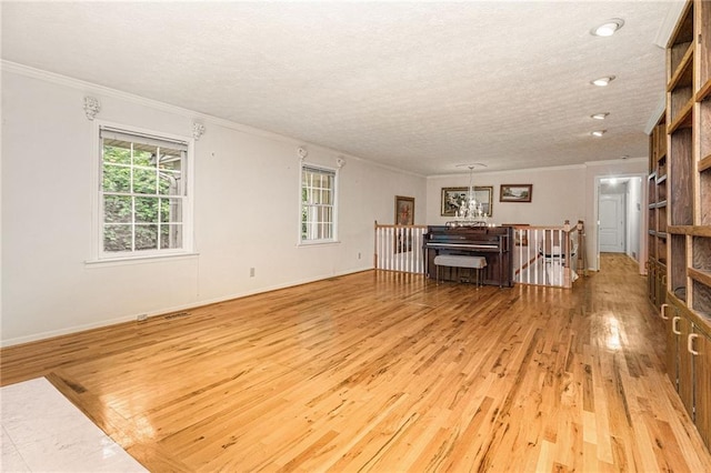 5247 Yeager Rd, Douglasville, GA 30135 - living room featuring a chandelier, light wood finished floors, crown molding, plenty of natural light, and a textured ceiling